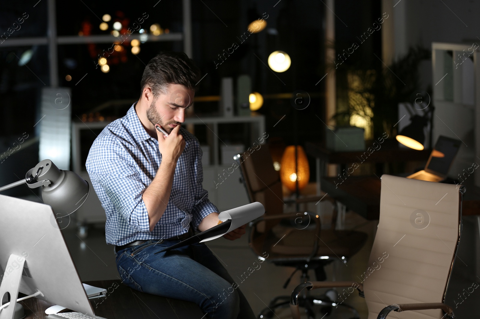 Photo of Young man working in office at night. Space for text