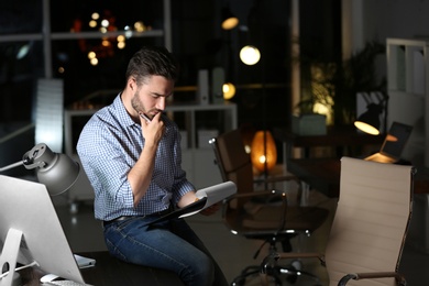 Young man working in office at night. Space for text