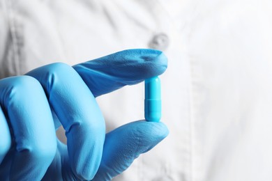 Doctor holding pill, closeup. Space for text