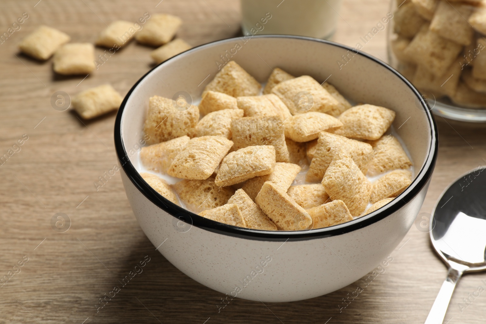 Photo of Bowl with tasty corn pads and milk on wooden table, closeup