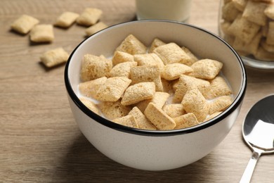 Photo of Bowl with tasty corn pads and milk on wooden table, closeup