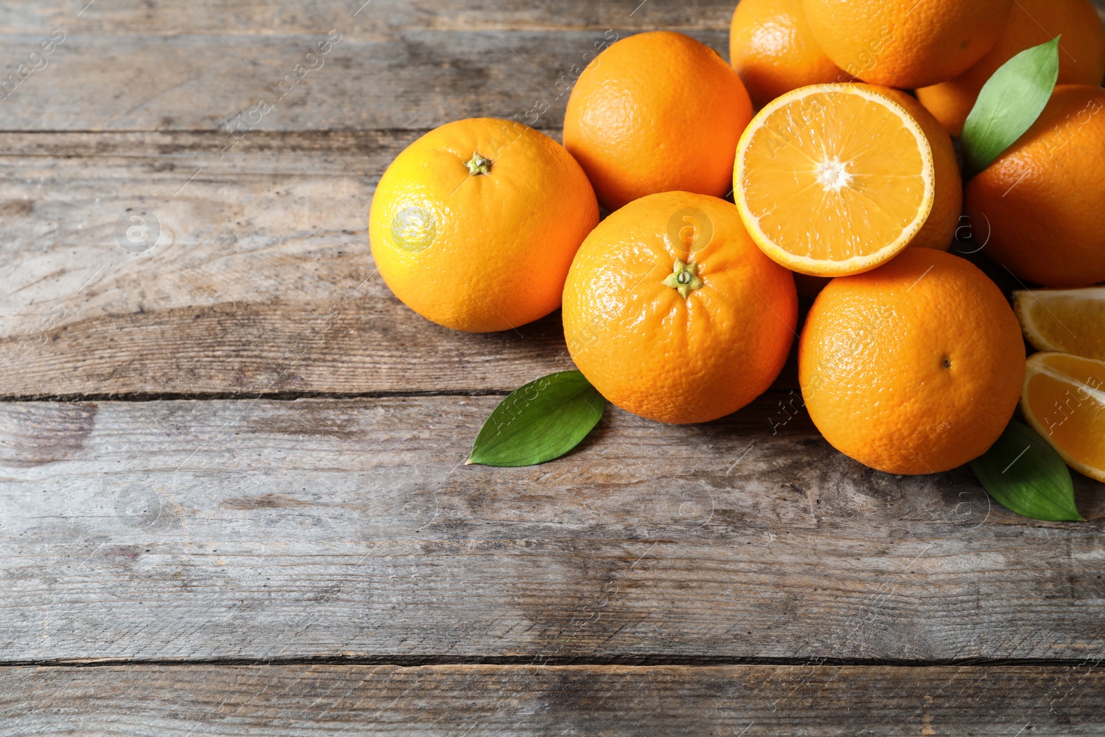 Photo of Fresh oranges with leaves on wooden background. Space for text