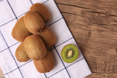 Heap of whole and cut fresh kiwis on wooden table, top view. Space for text