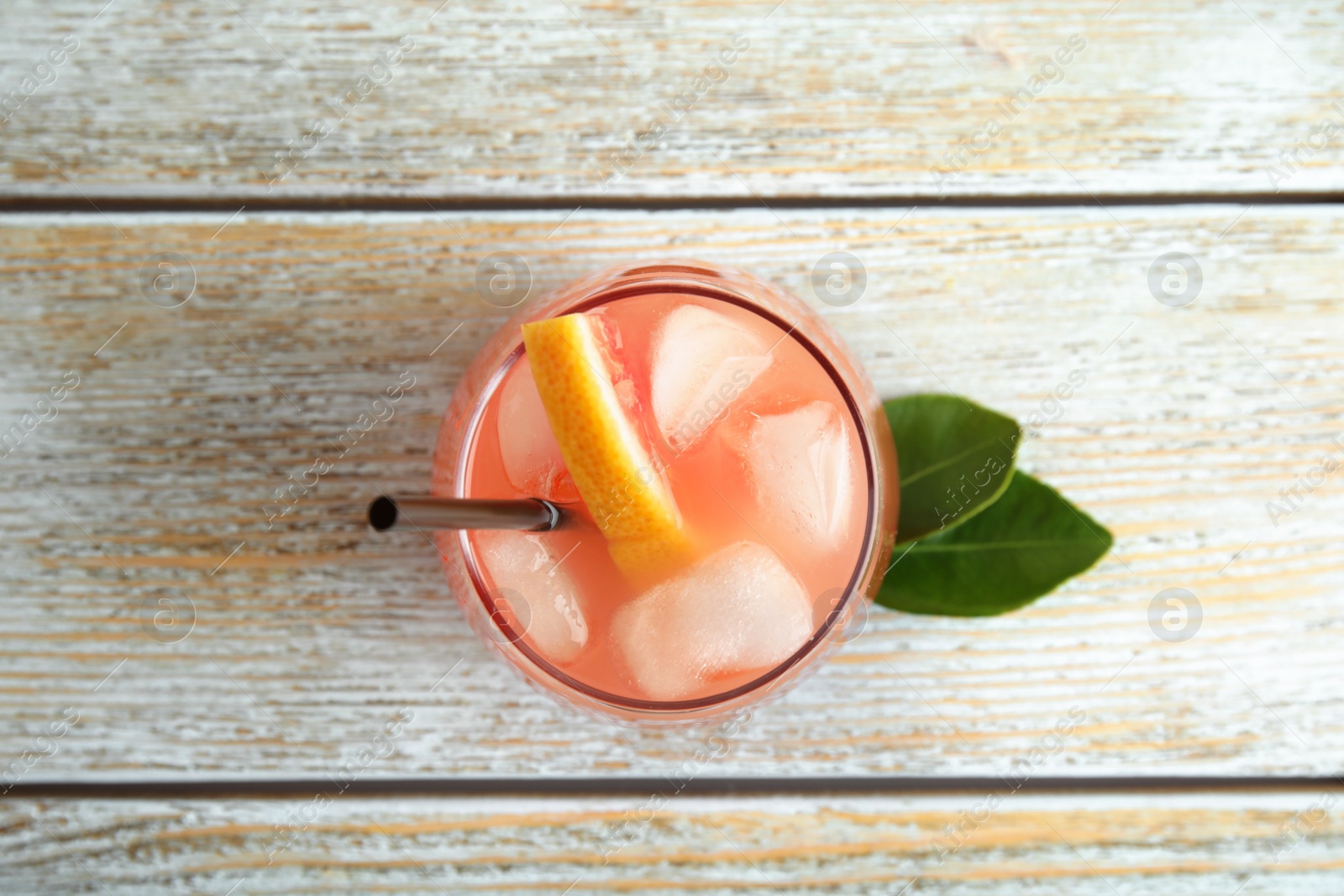 Photo of Glass of grapefruit cocktail on wooden table, top view