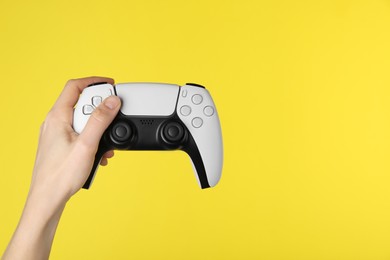 Woman with game controller on yellow background, closeup. Space for text