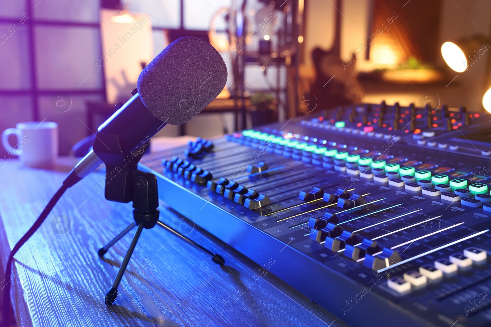 Photo of Microphone and professional mixing console on table in radio studio
