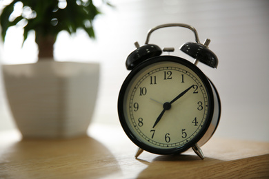 Photo of Alarm clock on wooden table at home. Morning time