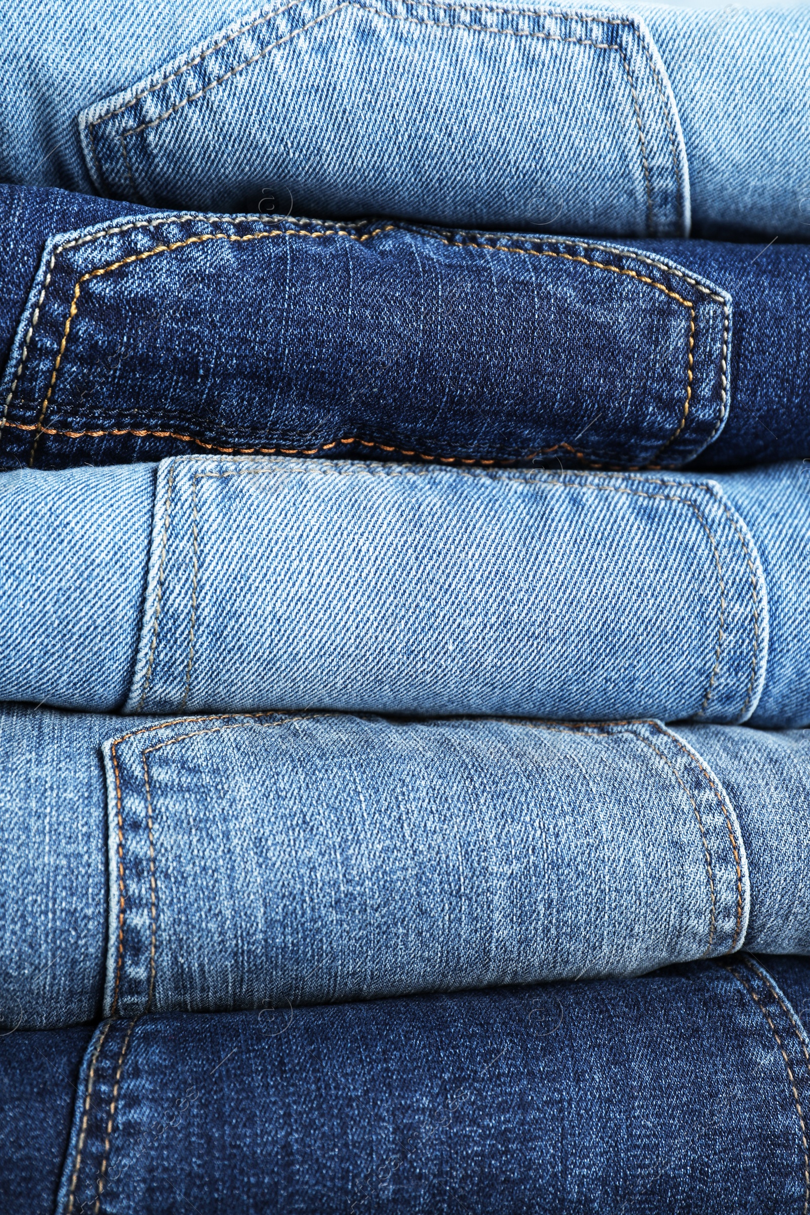 Photo of Stack of different jeans as background, closeup