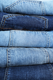 Photo of Stack of different jeans as background, closeup