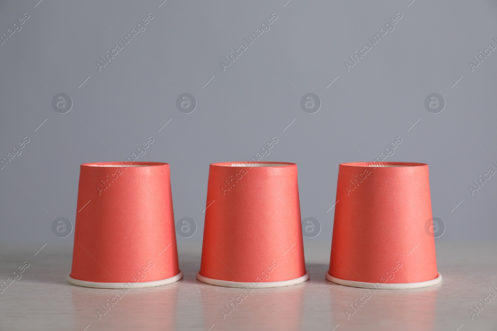 Photo of Shell game. Three red cups on light table