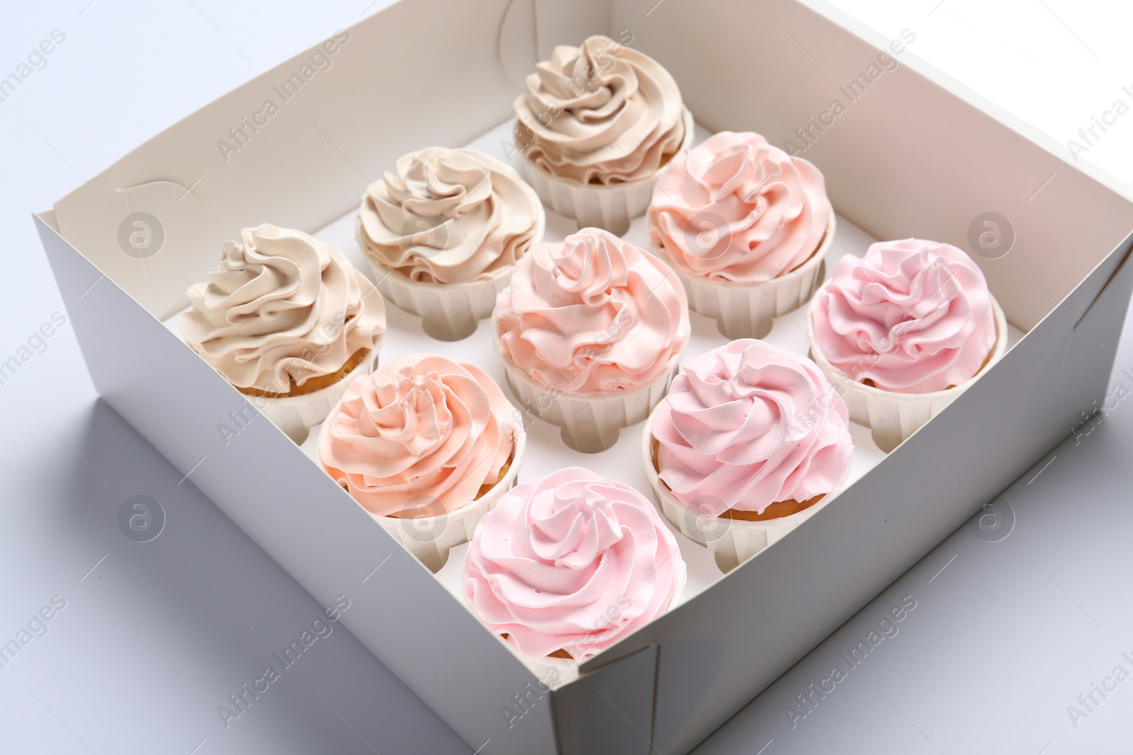 Photo of Tasty cupcakes in box on white background, closeup