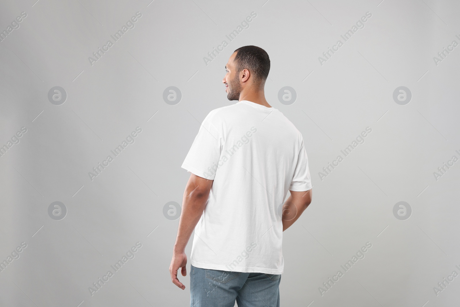 Photo of Man wearing white t-shirt on gray background, back view