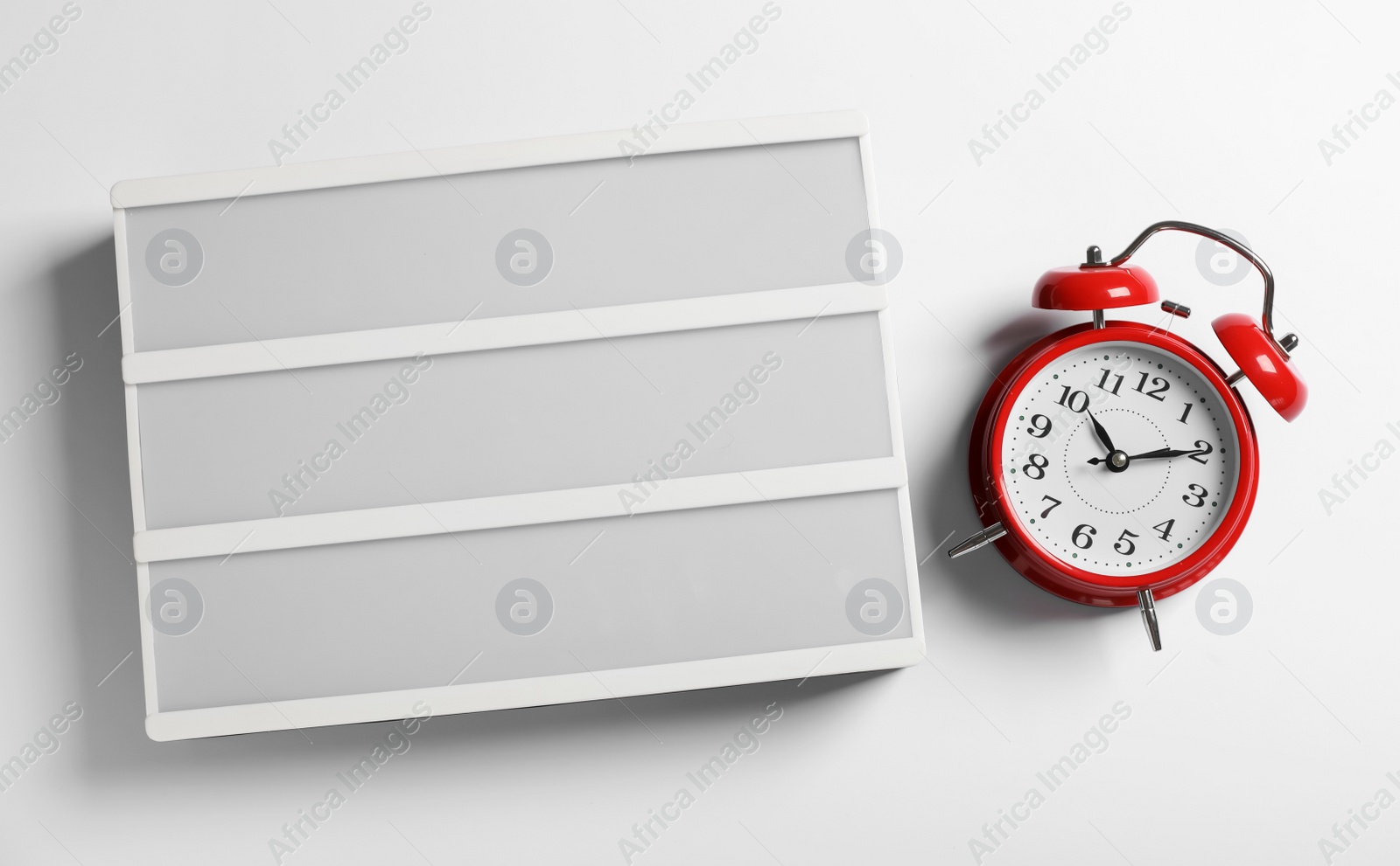 Photo of Blank letter board and alarm clock on white background, flat lay