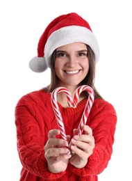 Photo of Pretty woman in Santa hat and sweater making heart with candy canes on white background