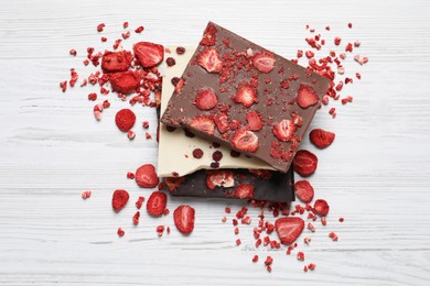 Photo of Different chocolate bars with freeze dried fruits on white wooden table, flat lay