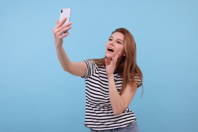 Photo of Beautiful woman taking selfie on light blue background