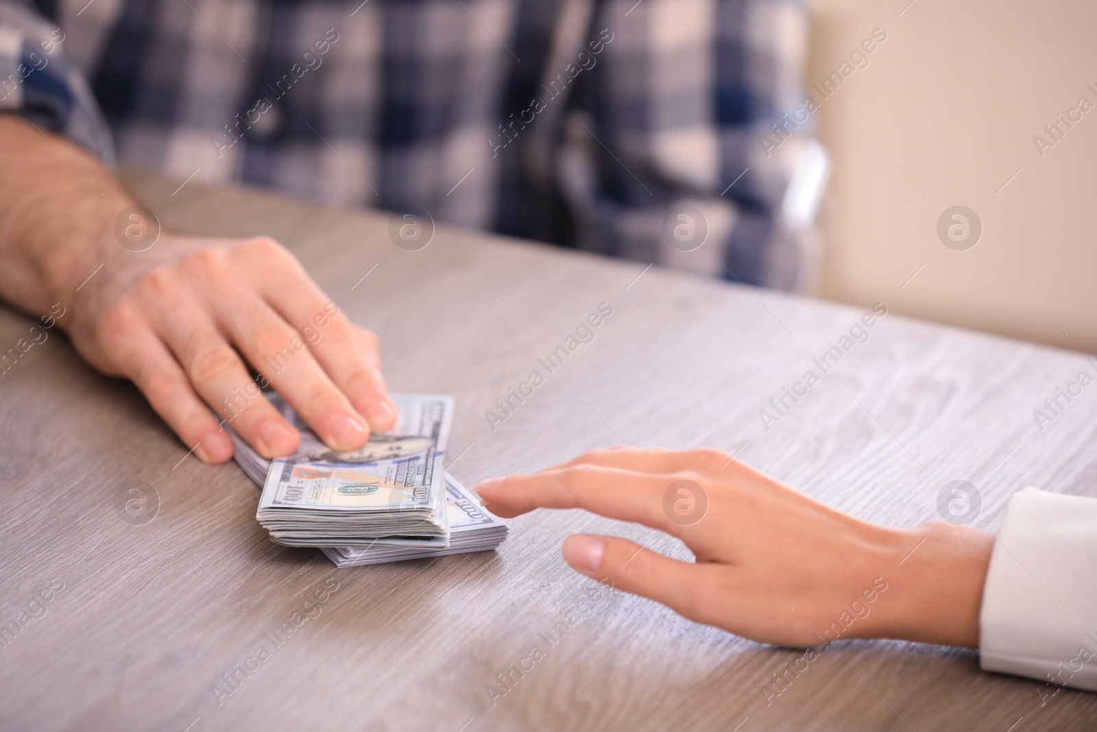 Photo of Man giving dollar bills to businesswoman at wooden table, closeup