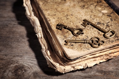 Photo of Old vintage keys with book on wooden background, space for text