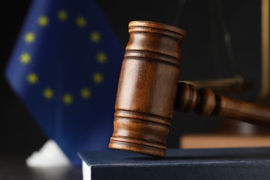 Photo of Closeup view of wooden judge's gavel on book near European Union flag