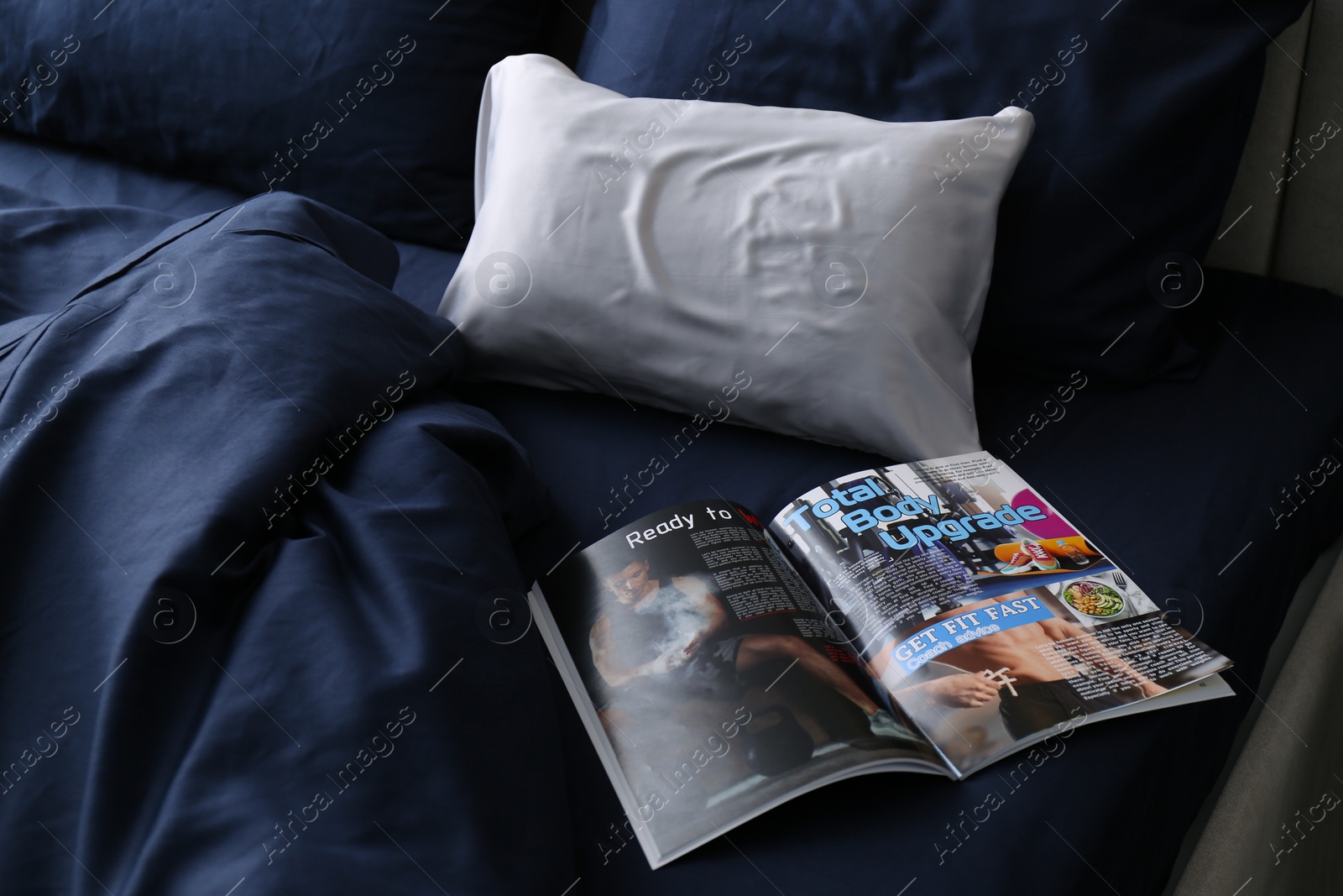 Photo of Open magazine on bed with stylish silky linens