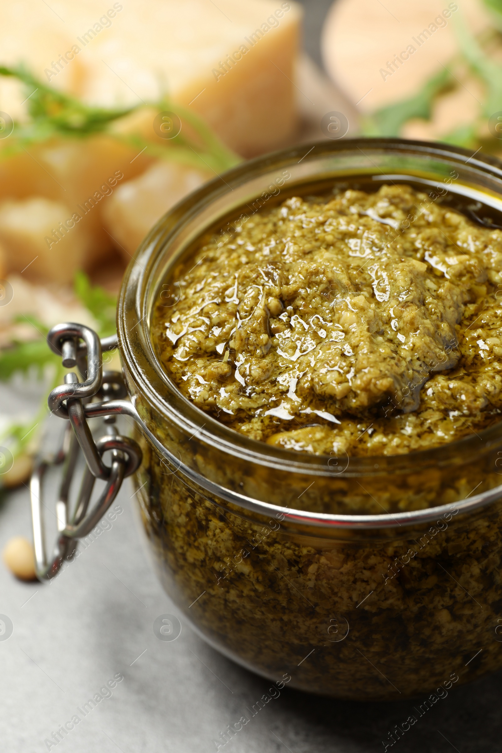 Photo of Jar of tasty arugula pesto on table, closeup