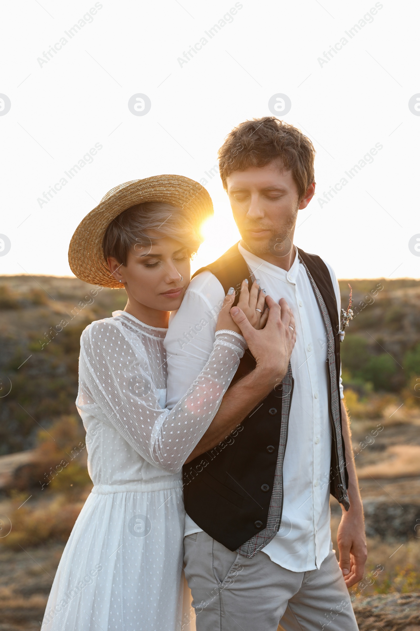 Photo of Happy bride and groom standing outdoors at sunset