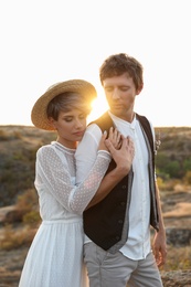 Photo of Happy bride and groom standing outdoors at sunset