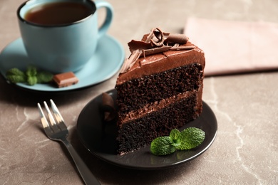 Photo of Slice of tasty chocolate cake and cup of tea served on table