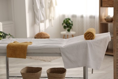 Photo of Comfortable massage table with clean towels in spa center