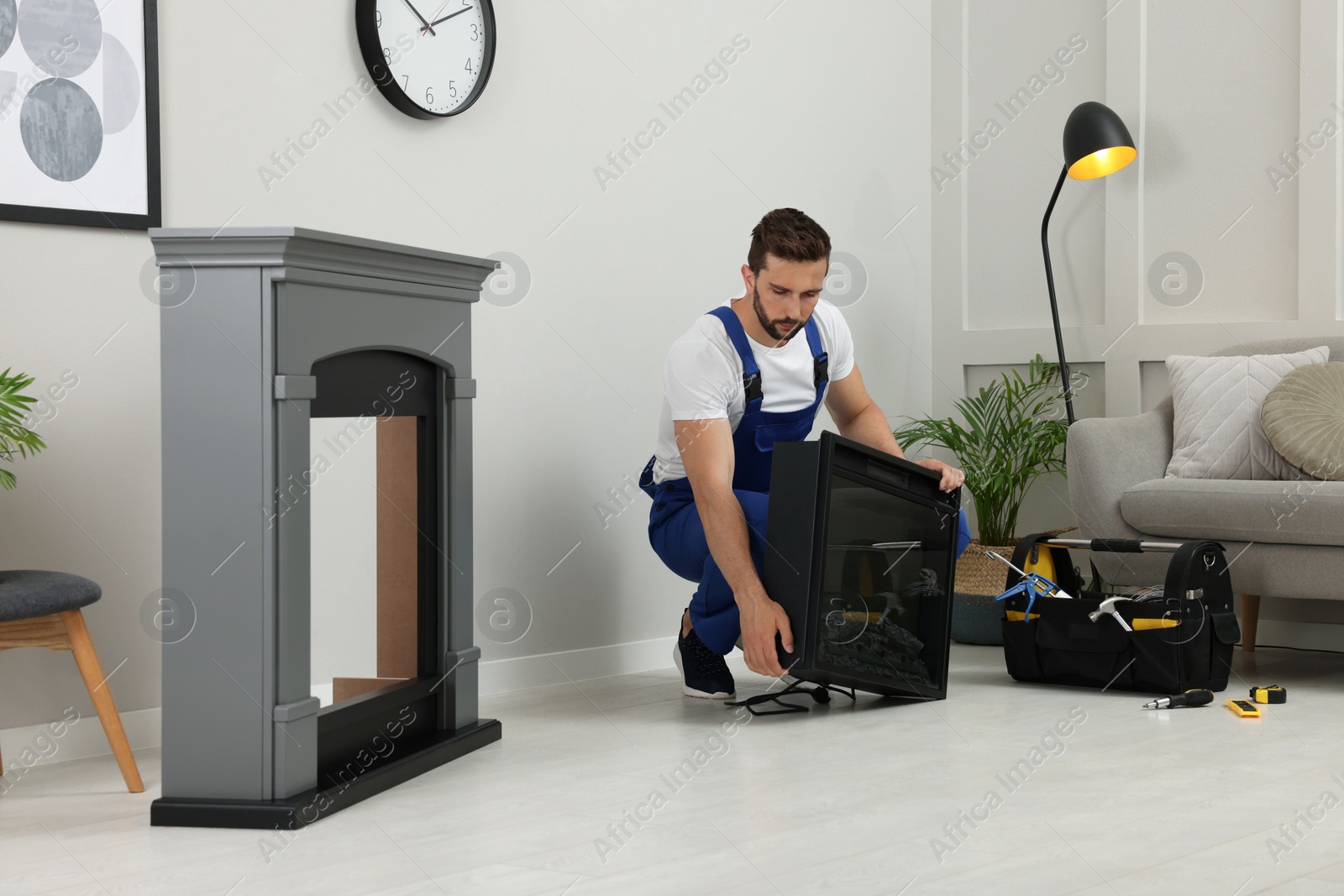 Photo of Professional technician installing electric fireplace in room