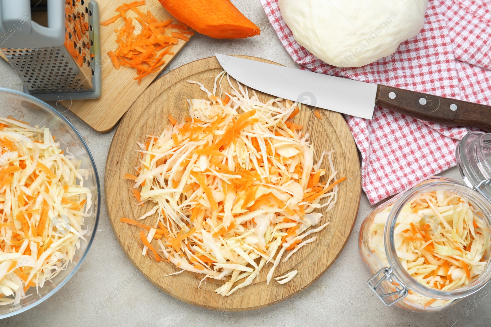 Photo of Cooking delicious sauerkraut soup. Fresh chopped carrot and cabbage on light grey table, flat lay