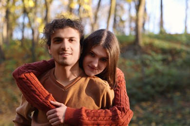 Photo of Happy young couple spending time together in autumn park, space for text. Dating agency