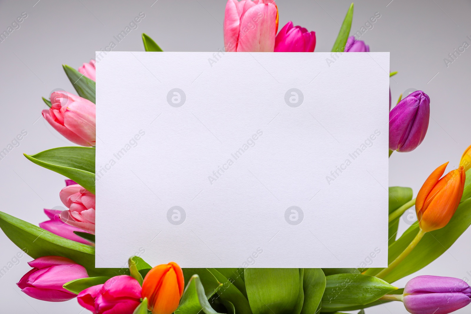 Photo of Blank birthday card on beautiful tulip flowers against grey background, flat lay. Space for text