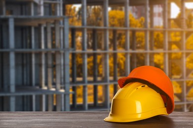 Safety equipment. Hard hats on wooden surface near unfinished building outdoors, space for text