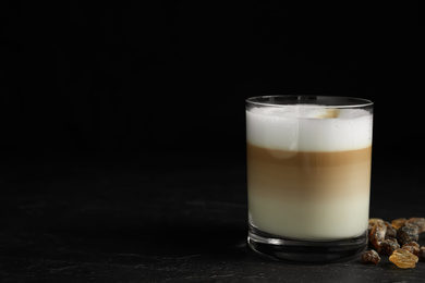 Photo of Delicious latte macchiato on table against black background, space for text
