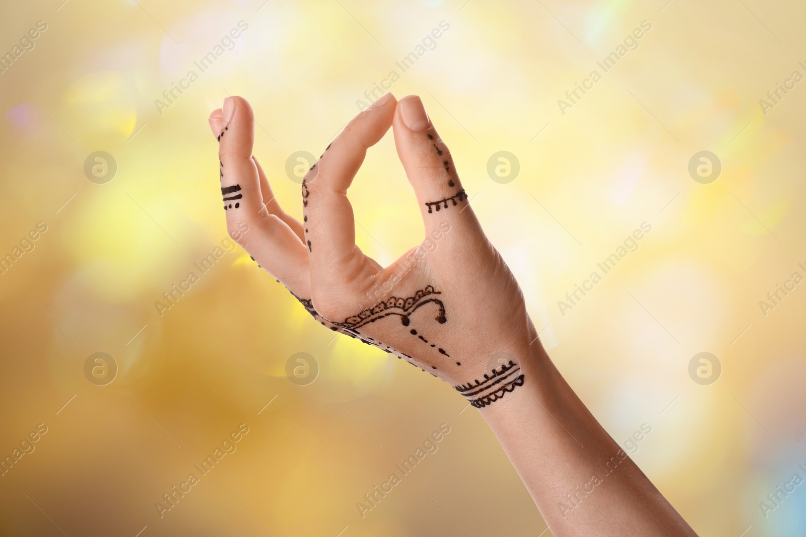 Image of Woman with henna tattoo on hand against blurred background, bokeh effect