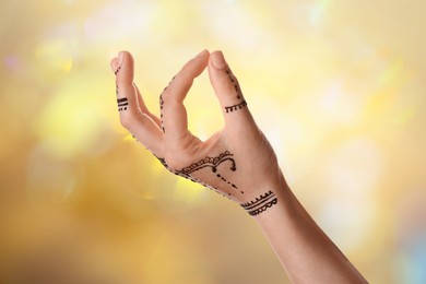 Image of Woman with henna tattoo on hand against blurred background, bokeh effect