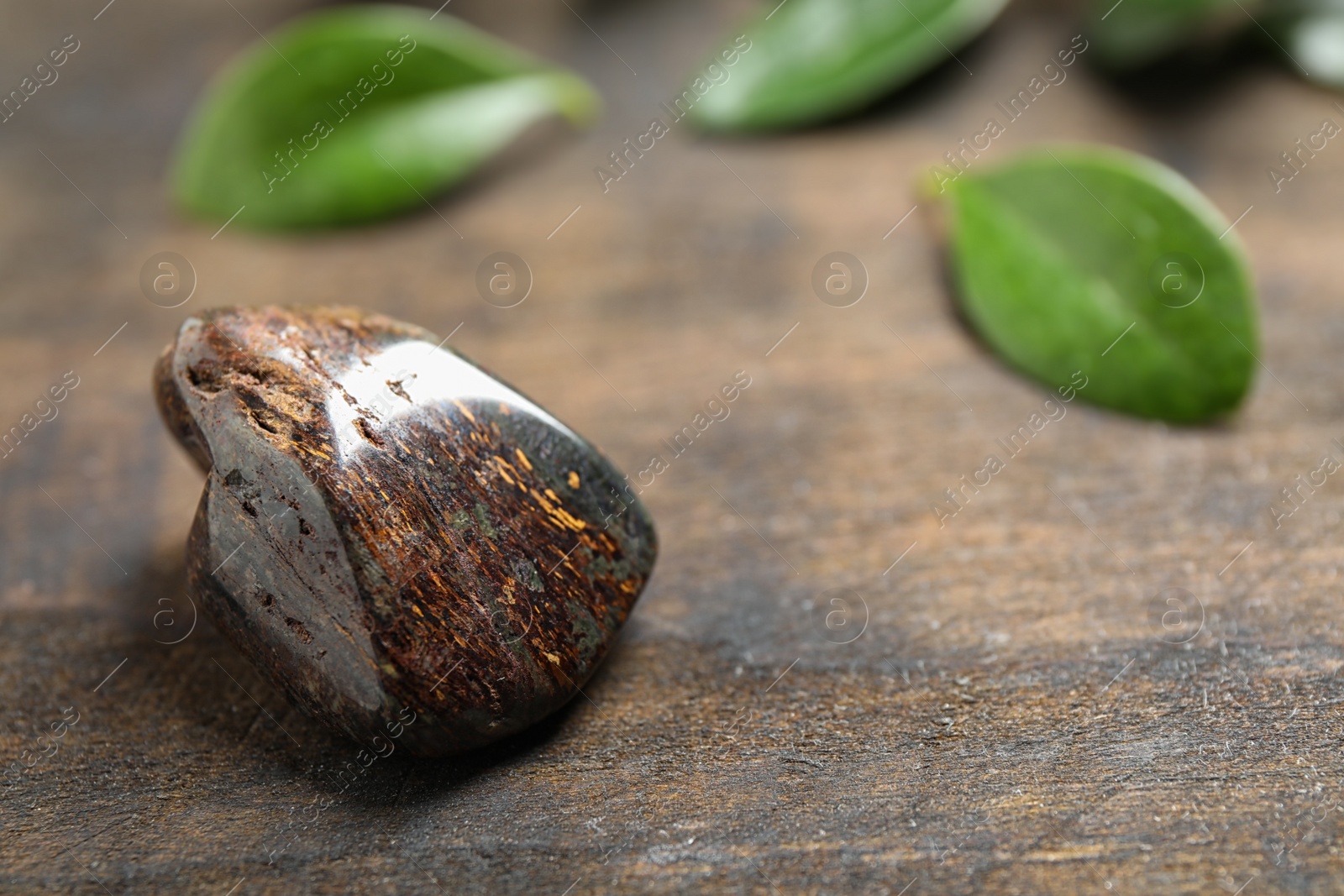 Photo of Beautiful brown bronzite gemstone on wooden table