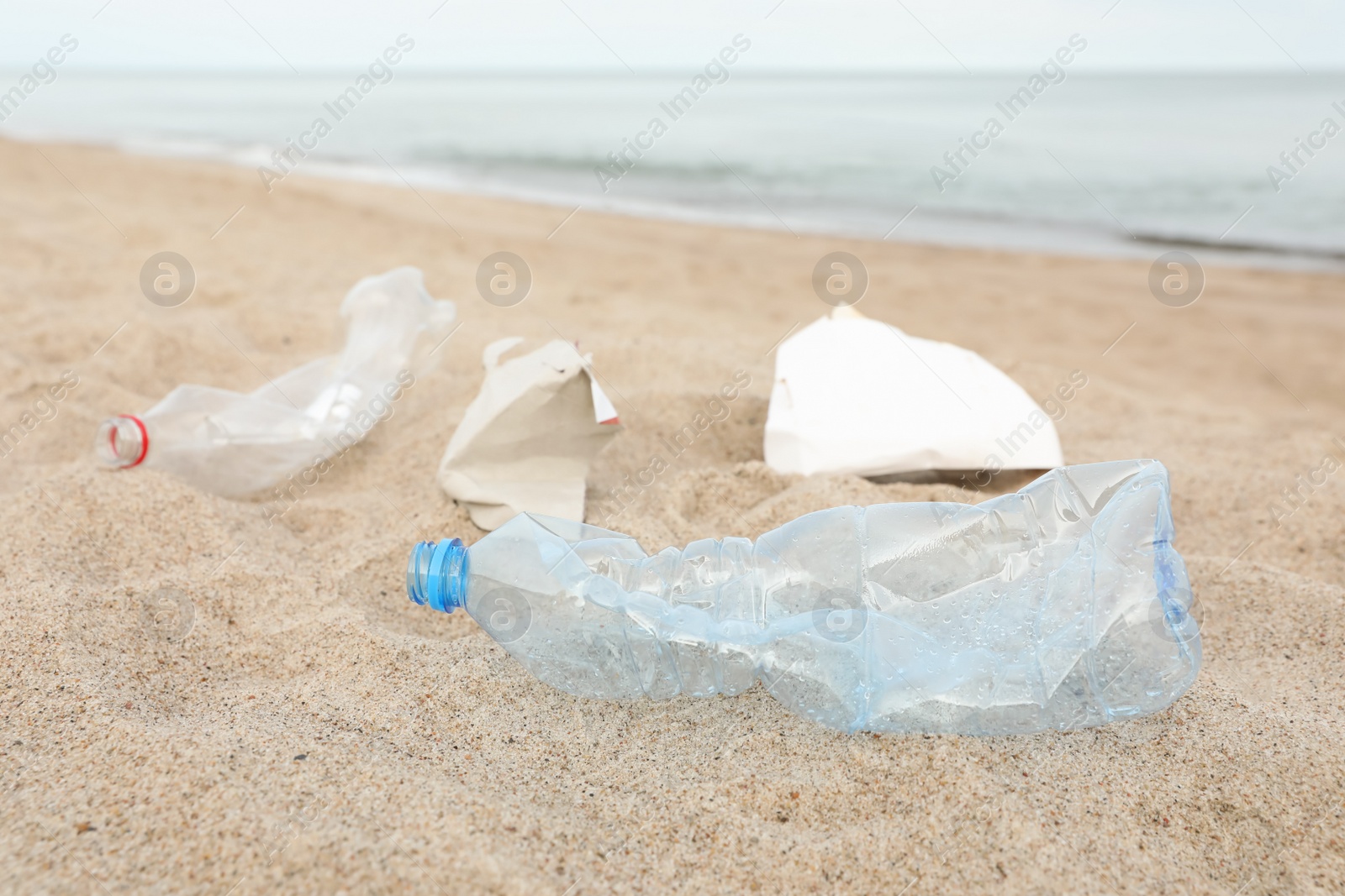 Photo of Garbage scattered on beach near sea, closeup. Recycling problem