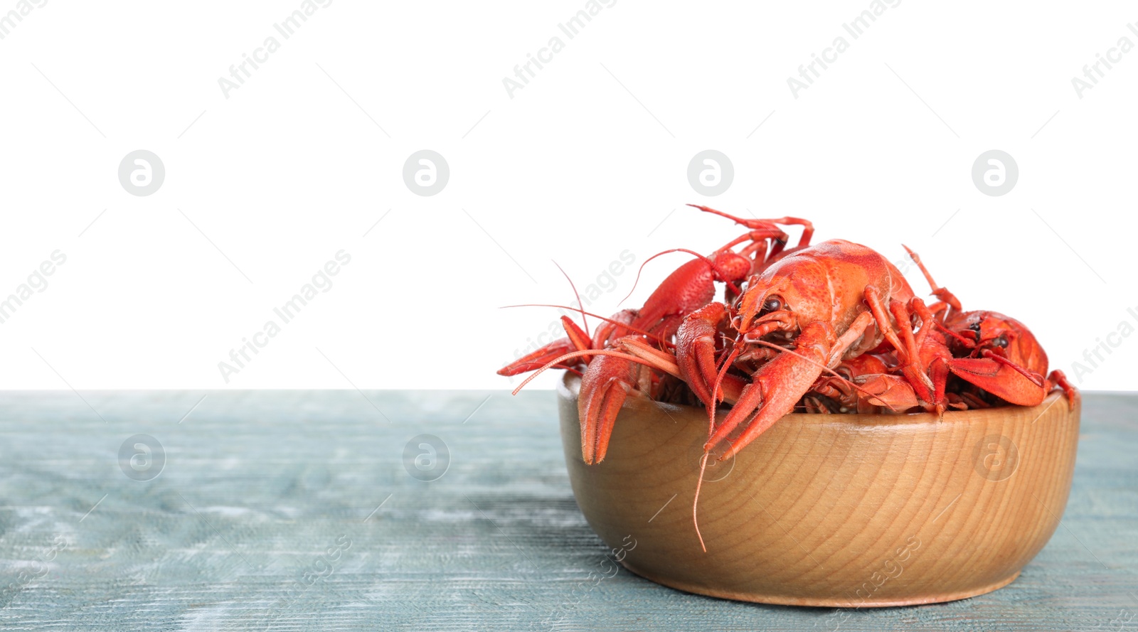 Photo of Delicious boiled crayfishes in bowl on wooden table against white background. Space for text