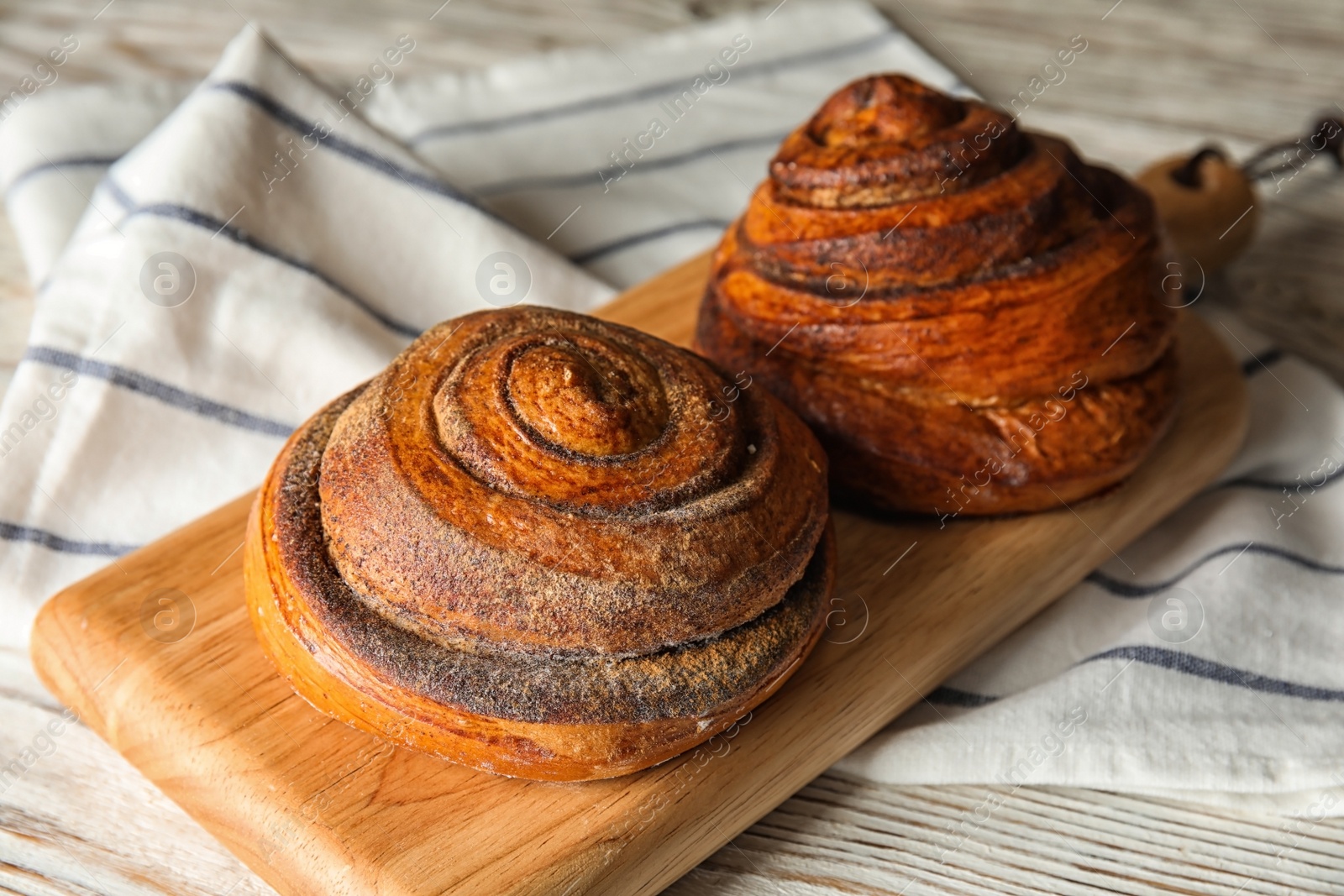 Photo of Wooden board with cinnamon rolls on table