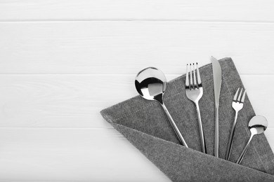 Photo of Stylish shiny cutlery set on white wooden table, flat lay. Space for text