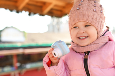 Cute little photographer with toy camera outdoors