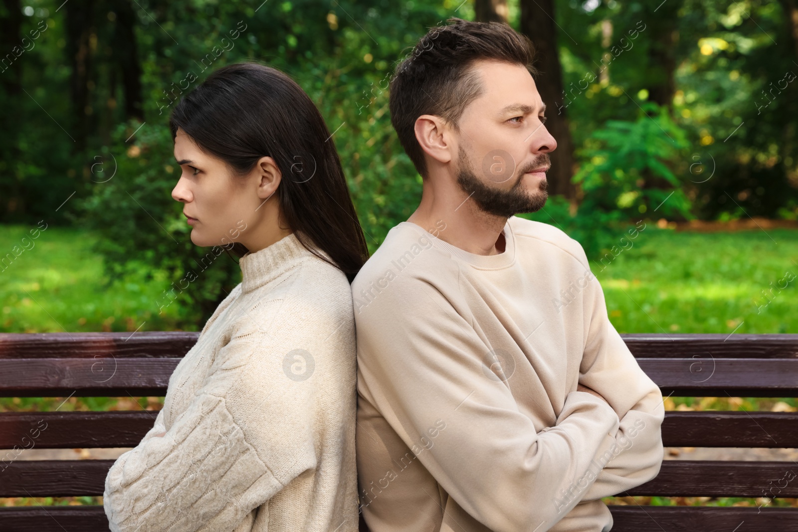 Photo of Upset arguing couple sitting on bench in park. Relationship problems