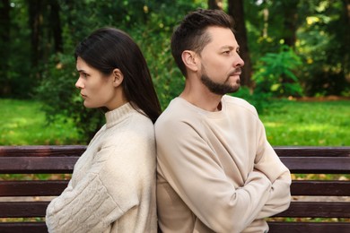 Photo of Upset arguing couple sitting on bench in park. Relationship problems