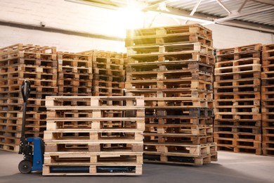 Image of Modern manual forklift and wooden pallets in warehouse