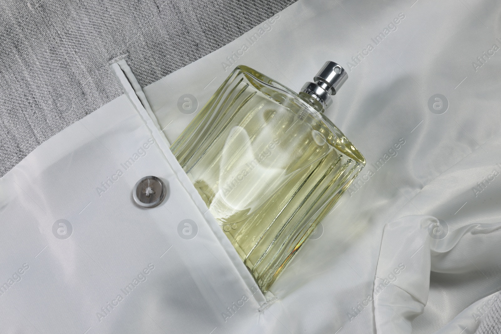 Photo of Luxury men's perfume in inner pocket of grey jacket, top view