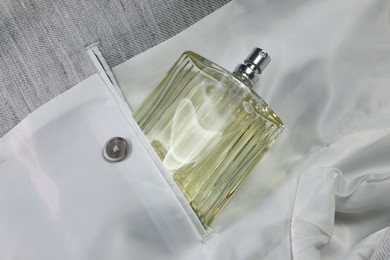 Photo of Luxury men's perfume in inner pocket of grey jacket, top view