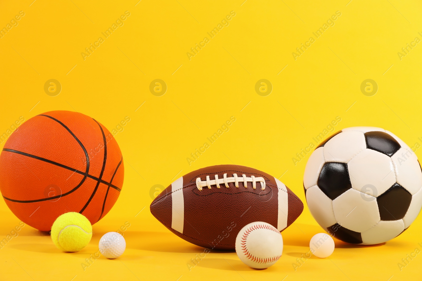 Photo of Many different sports balls on yellow background, space for text