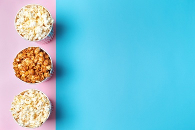 Different kinds of popcorn in paper cups on color background, top view. Space for text